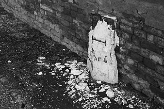 Broken concrete marker against old brick wall