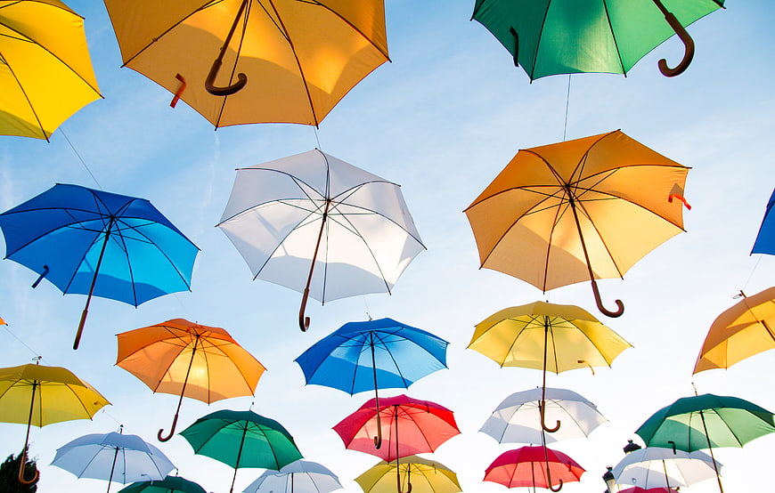 Colorful umbrellas hanging against a blue sky