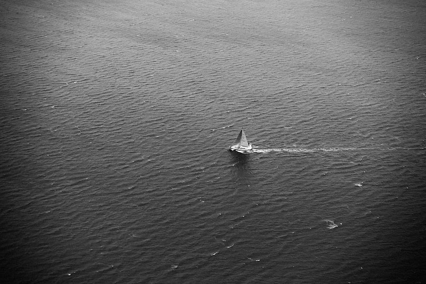 Lone Sailboat on Dark Ocean in Black and White