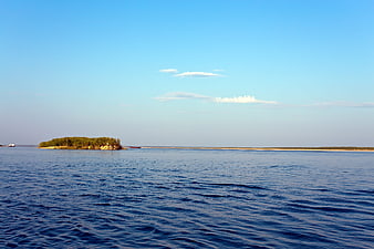 Serene River Landscape with Small Forested Island and Blue Sky