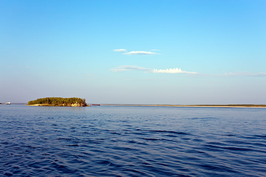 Serene River Landscape with Small Forested Island and Blue Sky