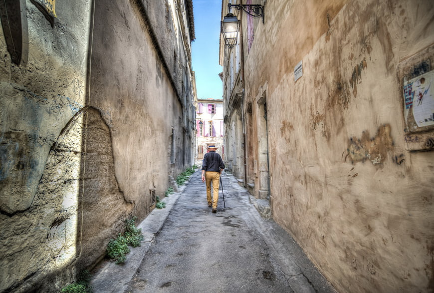 Senior man walking down narrow old European alleyway