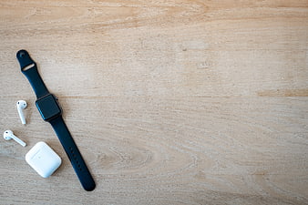 Smartwatch and Wireless Earbuds on Wooden Surface