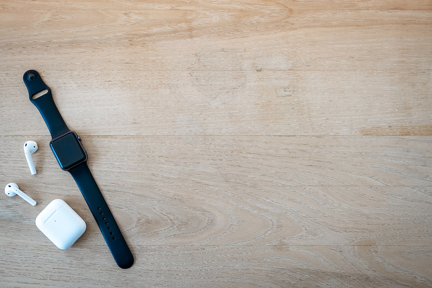 Smartwatch and Wireless Earbuds on Wooden Surface