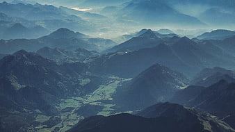 Misty mountain landscape with layered peaks and green valley