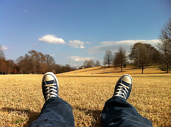 First person view of blue sneakers on grassy hill