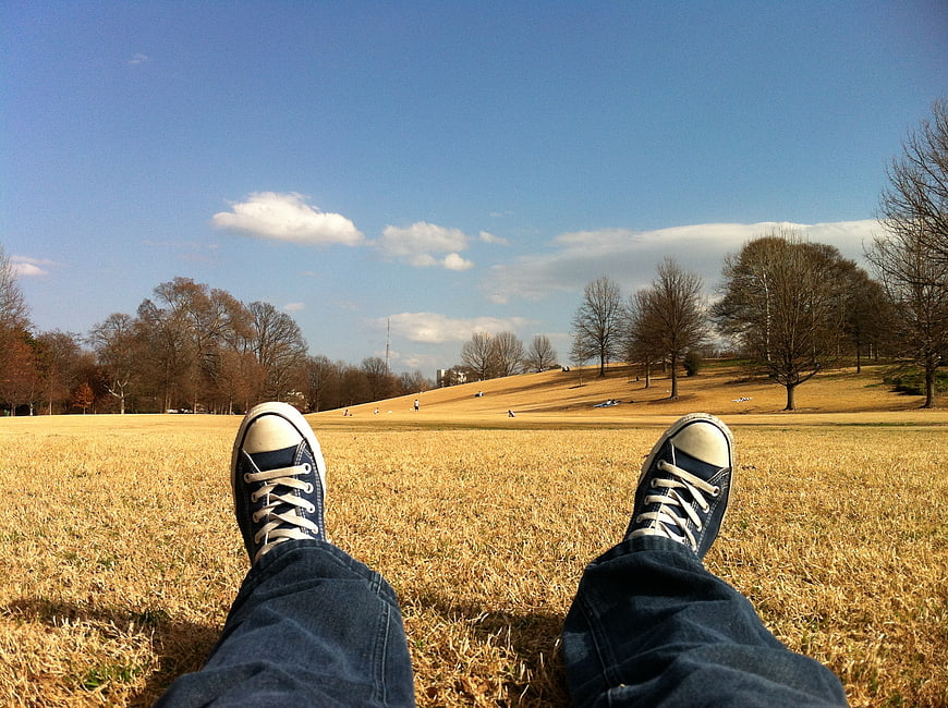 First person view of blue sneakers on grassy hill