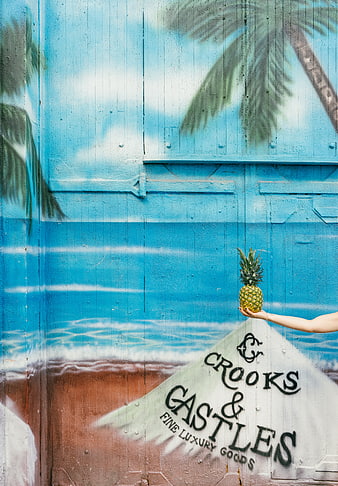 Hand holding pineapple against tropical beach mural wall