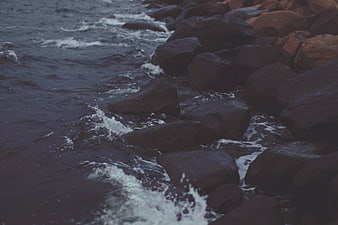 Dark Ocean Waves Crashing Against Rocky Shoreline