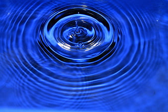 Blue water droplet creating ripples in a pool