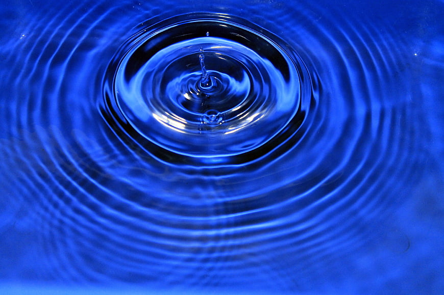 Blue water droplet creating ripples in a pool