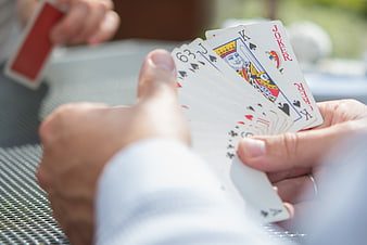 Hands holding playing cards outdoors