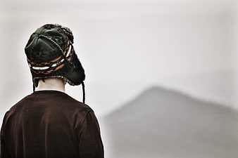 Man in Trapper Hat Looking at Foggy Mountain