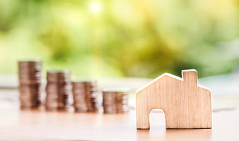 Wooden house model with stacks of coins for real estate investment