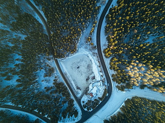 Aerial View of Snowy Forest with Winding Road and Cabin
