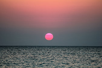 Pink Moon Rising Over Calm Ocean Horizon