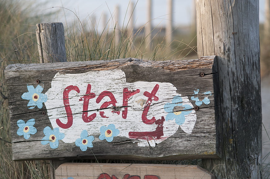 Rustic Wooden Start Sign with Blue Flowers on Beach