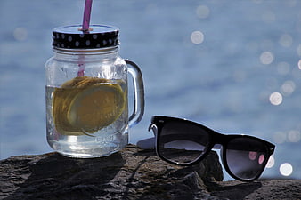 Mason jar lemonade and sunglasses on a rock by the water