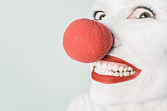 Close-up of creepy clown face with red nose and white makeup