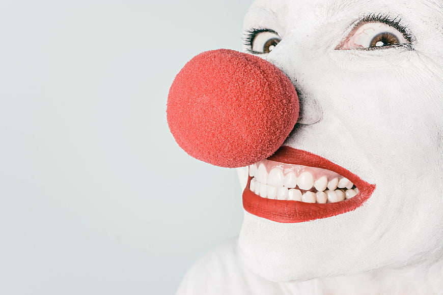 Close-up of creepy clown face with red nose and white makeup