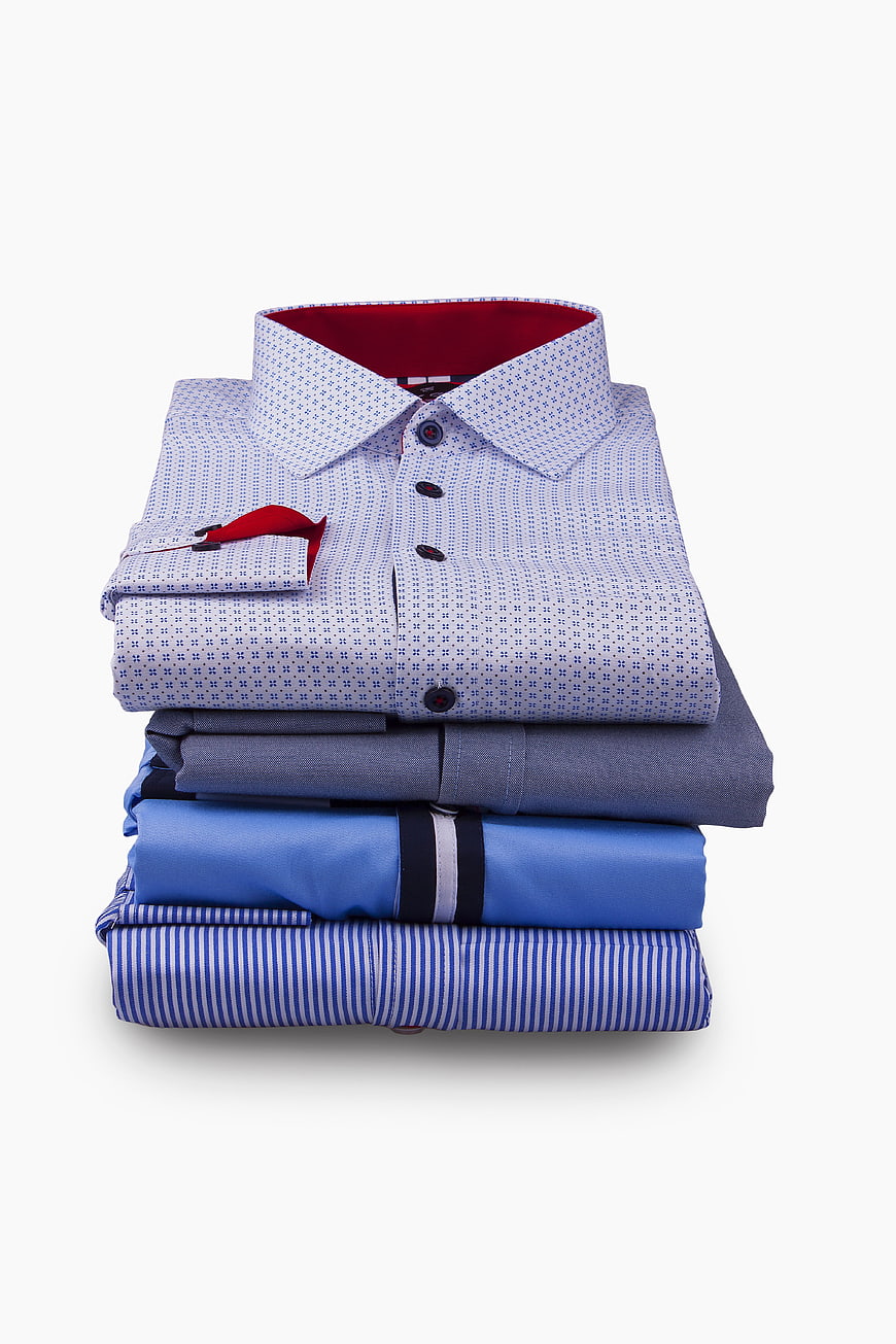 Stack of folded men's dress shirts on white background