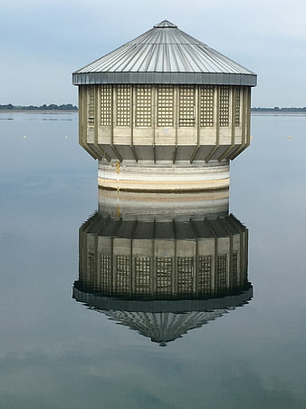 Symmetrical concrete water intake tower with perfect reflection
