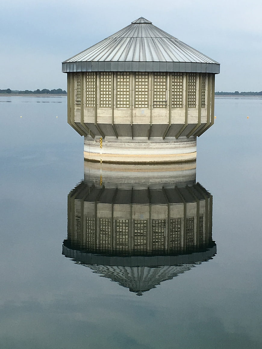 Symmetrical concrete water intake tower with perfect reflection