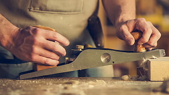 Carpenter using hand plane on wood block