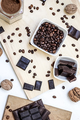 Flat lay of dark chocolate, coffee beans, and cocoa powder on wood