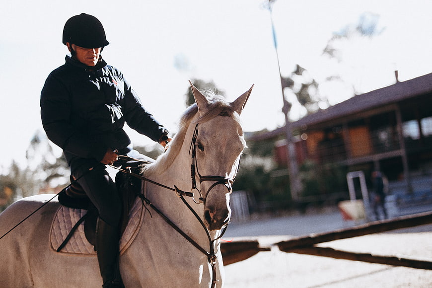 Man Riding White Horse in Outdoor Arena