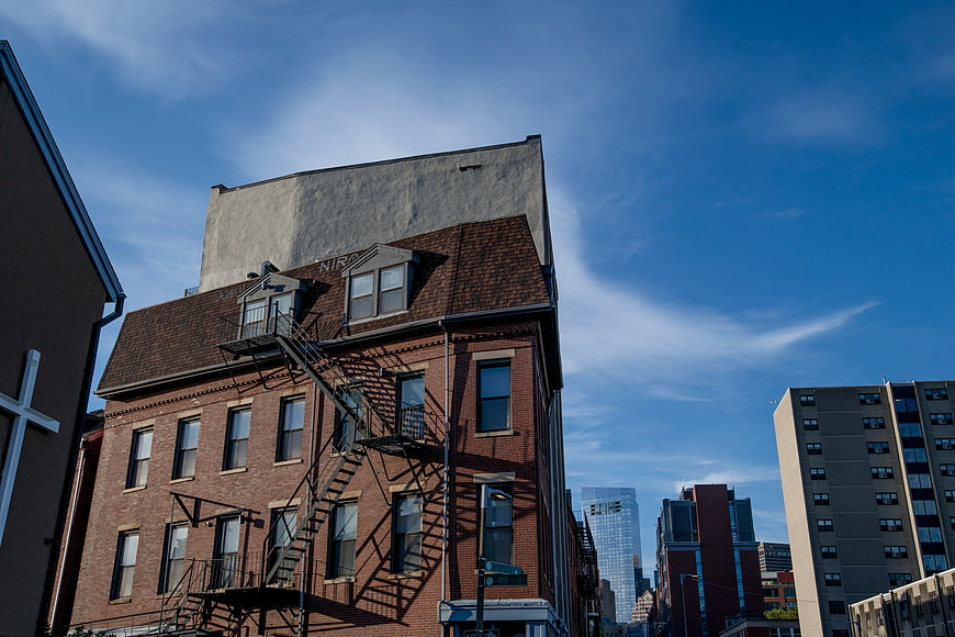 Low angle view of red brick building with fire escape against blue sky