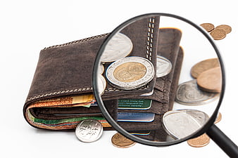 Magnifying glass inspecting coins in a leather wallet