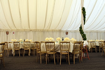 Elegant wedding reception tent with round tables and Chiavari chairs