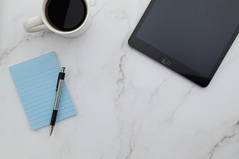 Flat lay workspace with tablet, coffee, and notepad on marble