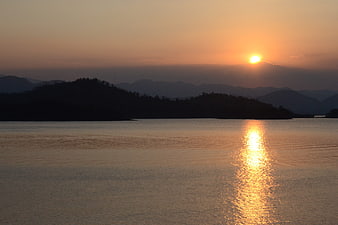 Golden Sunset Over Calm Lake With Mountain Silhouettes