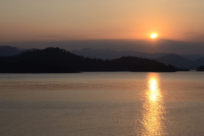 Golden Sunset Over Calm Lake With Mountain Silhouettes