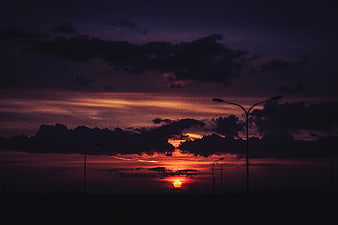 Dramatic sunset with street lamp silhouettes and dark clouds