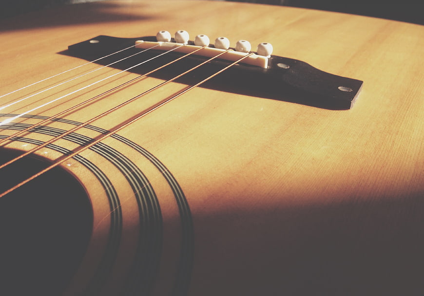 Close-up of acoustic guitar bridge and strings in warm sunlight