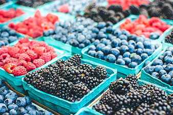 Fresh raspberries, blueberries, and blackberries in market baskets