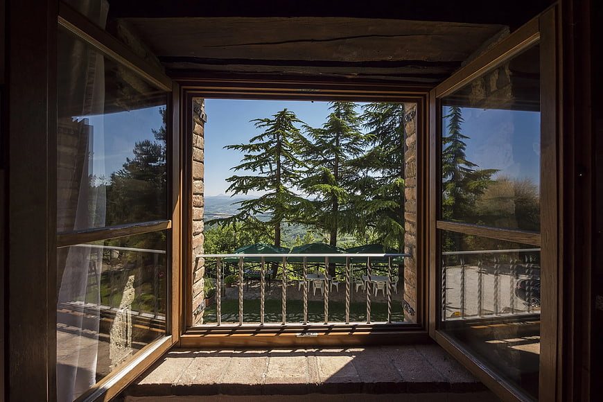 Open wooden window view of pine trees and balcony