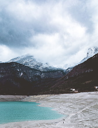 Turquoise lake with snow-capped mountains and cloudy sky