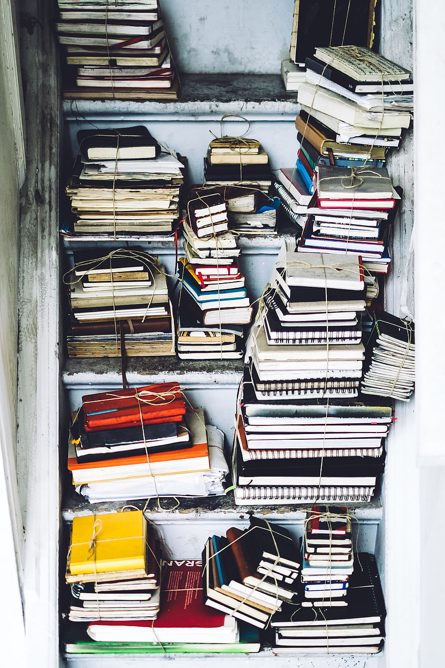 Stacks of old books tied with twine on shelves