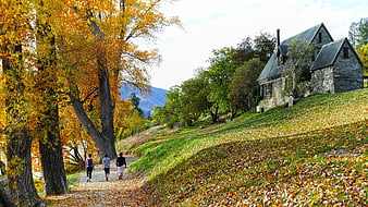 Autumn Landscape with Stone Church and Walking Hikers