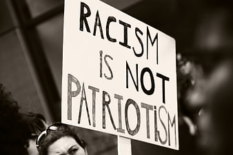 Protest sign reading racism is not patriotism in black and white