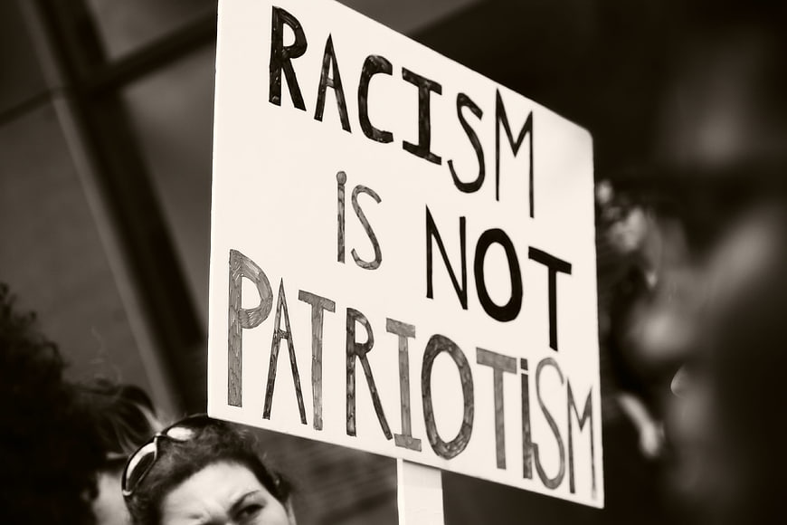 Protest sign reading racism is not patriotism in black and white