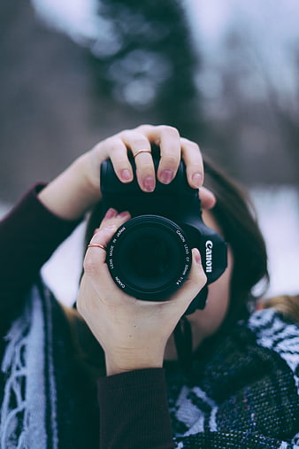 Woman holding Canon camera lens close-up