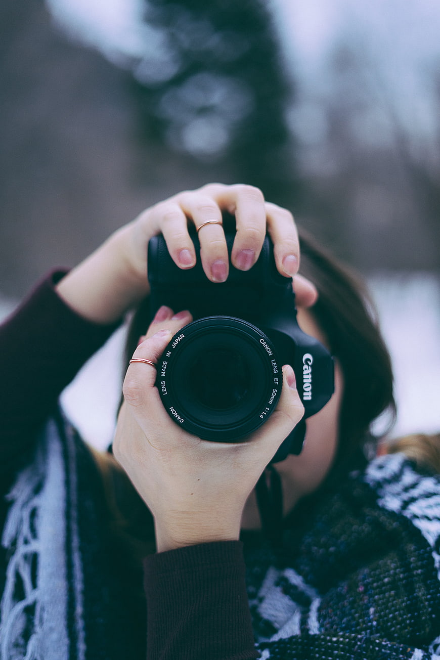 Woman holding Canon camera lens close-up