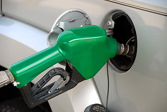 Green fuel nozzle inserted into silver car gas tank