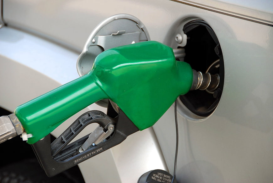 Green fuel nozzle inserted into silver car gas tank