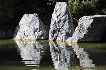Large gray rocks in calm water with reflections